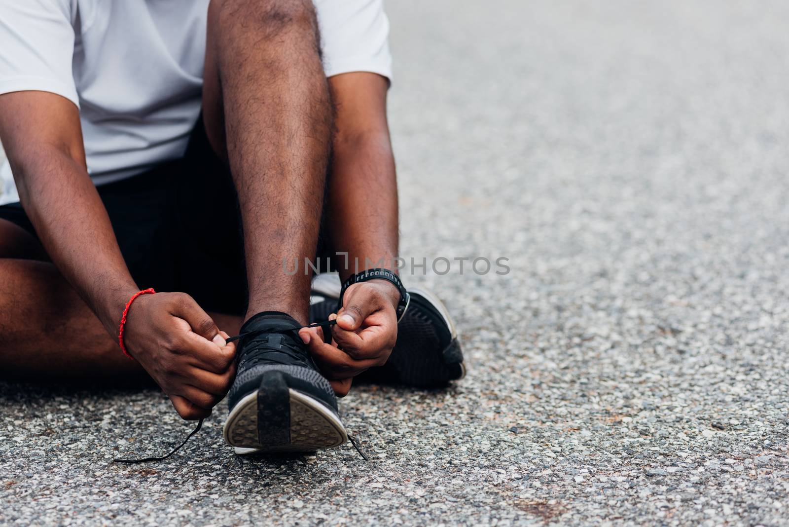 runner black man sitting shoelace trying running shoes by Sorapop