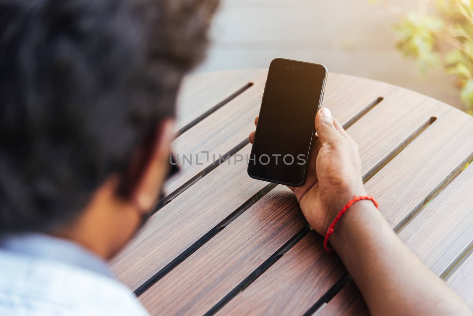 Happy Asian black businessman person holding a modern digital smart phone blank screen device technology and connecting networking online at the coffee cafe shop