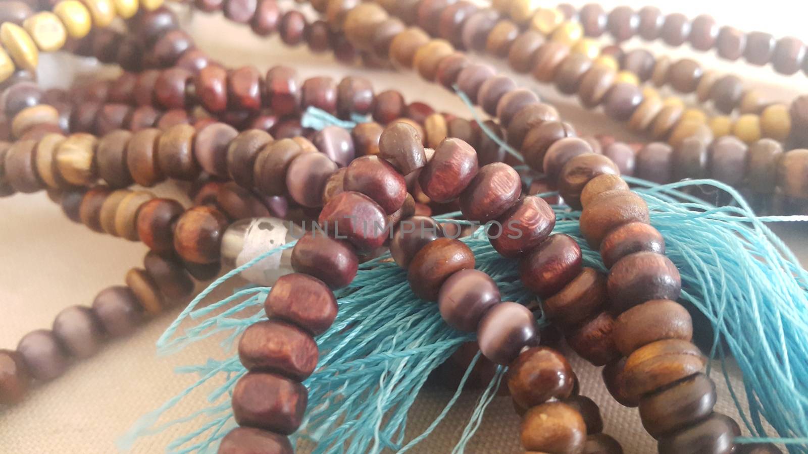 Beautiful wooden prayer beads or rosary placed over fabric background by Photochowk