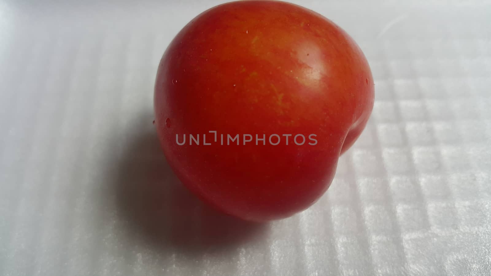 Closeup view of red plum on a white grey background. Freshly harvested plum making heart shape appearance in the view from angle.