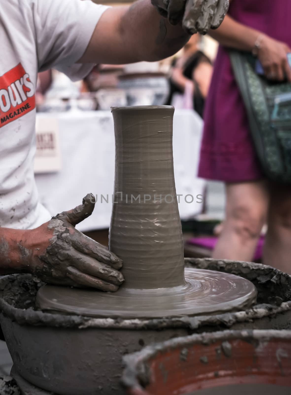 Hands of a potter shaping a clay pot on a potter wheel by Roberto