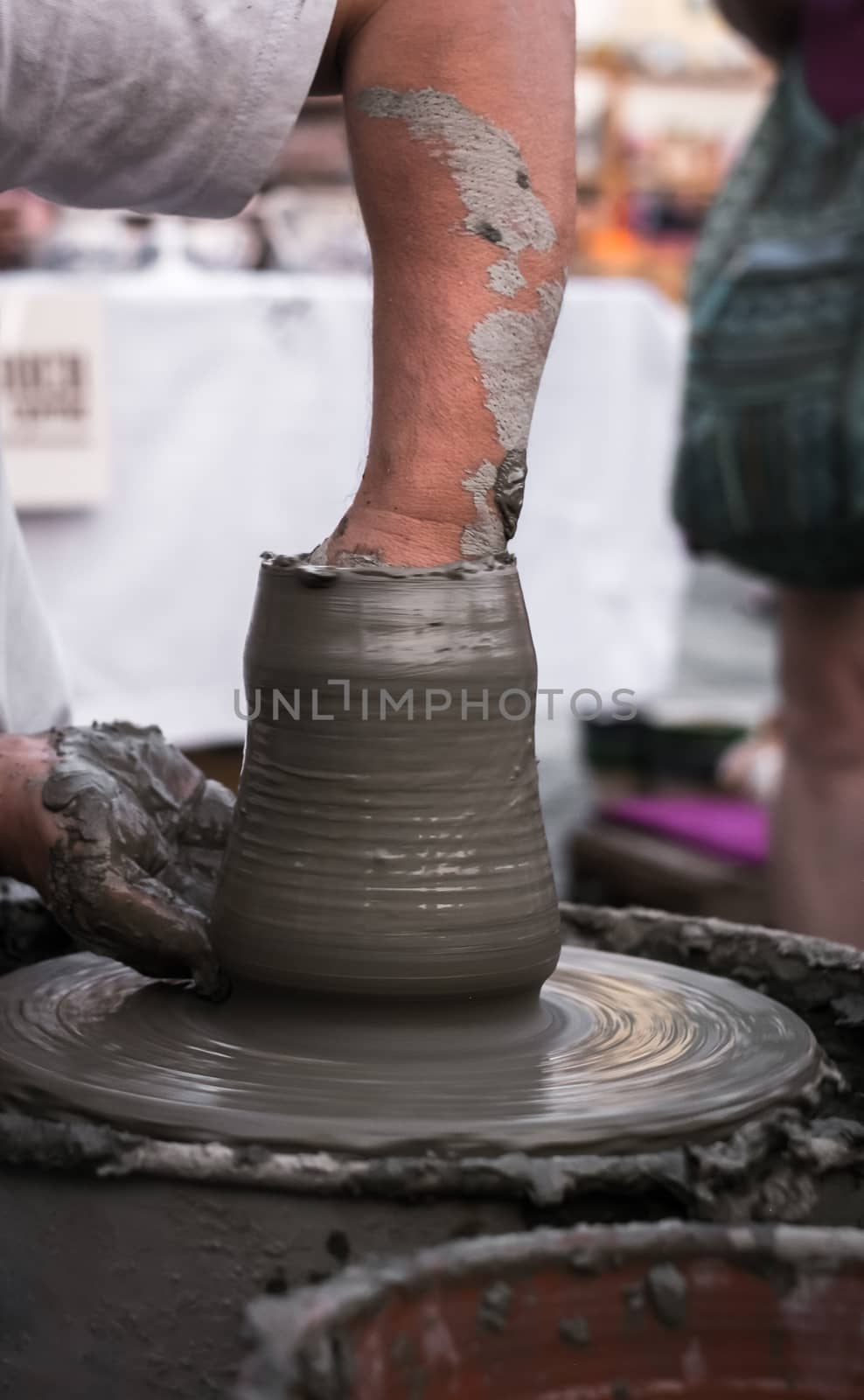 Hands of a potter shaping a clay pot on a potter wheel by Roberto