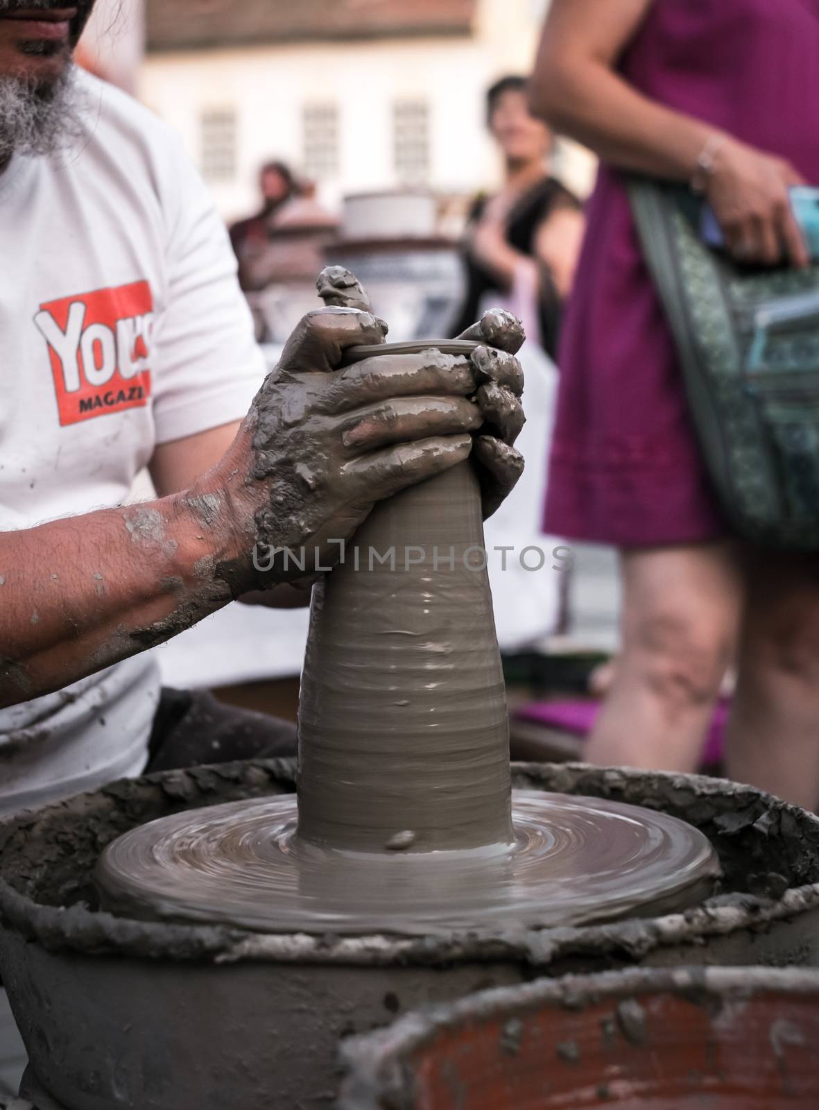 Hands of a potter shaping a clay pot on a potter wheel by Roberto