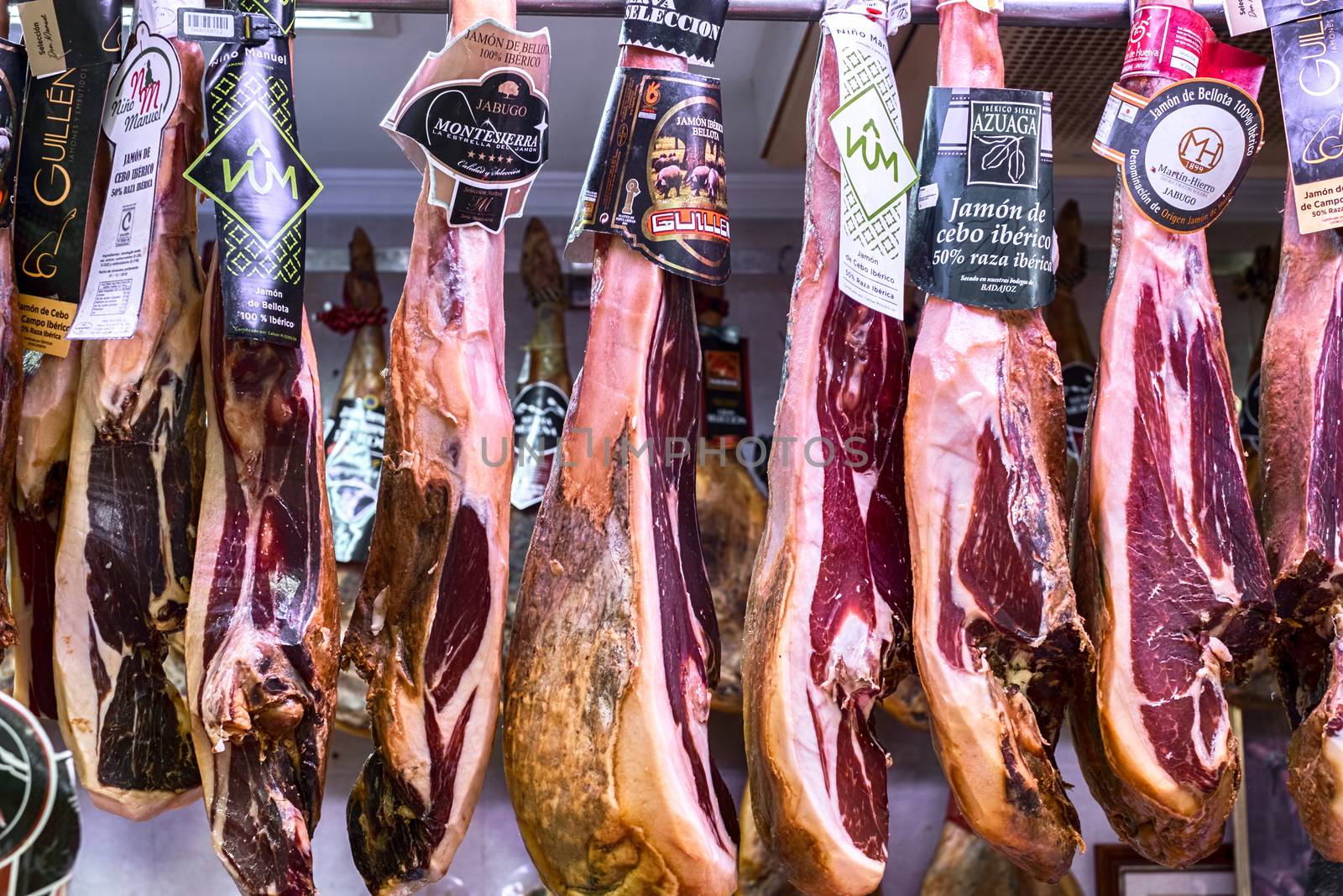 Malaga, Spain - May 24, 2018. Iberian ham (spanish prosciutto or jamon iberico) hanging at Ataranzanas Central Market, Malaga, Spain