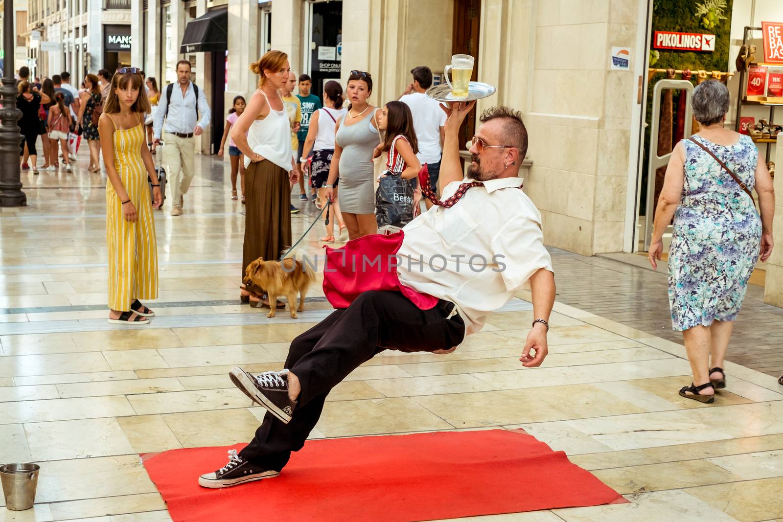 Malaga, Spain - August 03, 2018. This is a human sculpture featuring a waiter falling down on the Marques de Larios pedestrian, in the historic center of Malaga, Spain