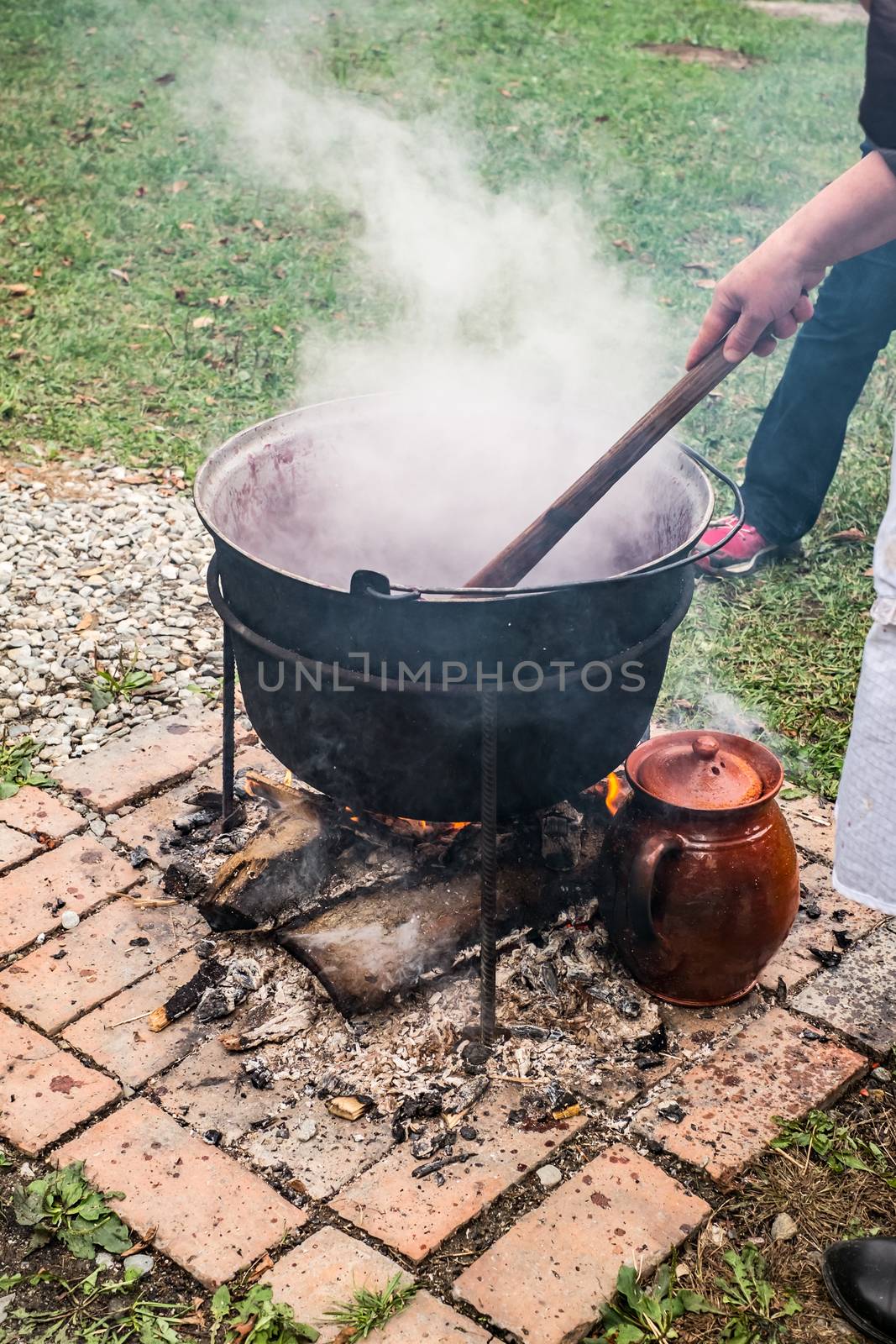 a country woman preparing a Romanian traditional food at the cauldron