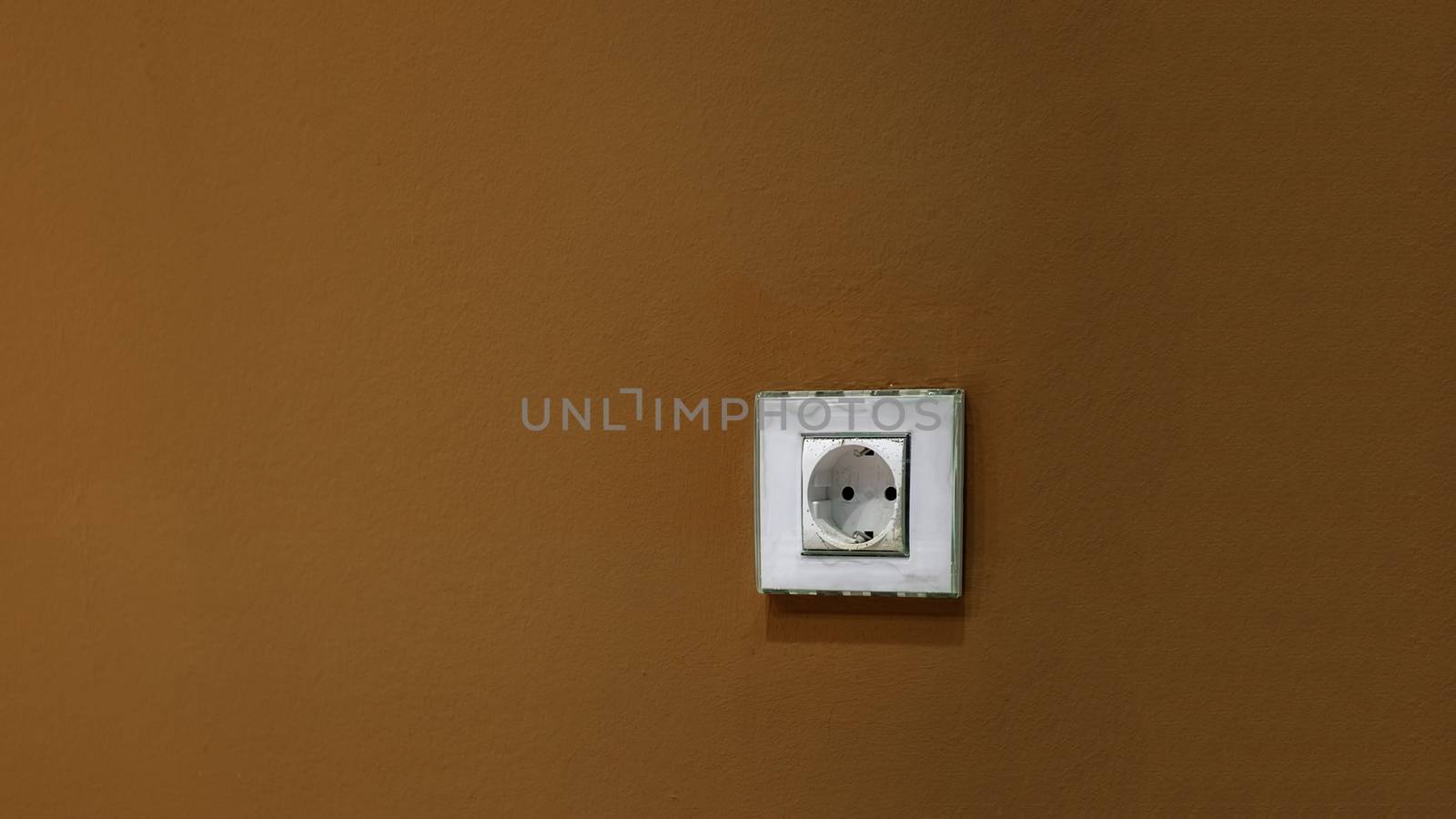 a white socket on the brown wall