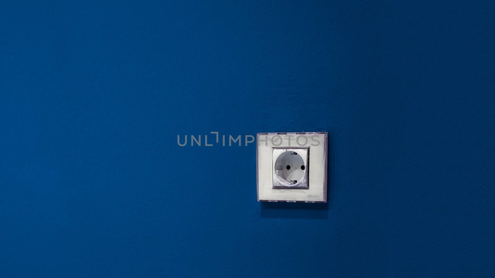 a white socket on the blue wall