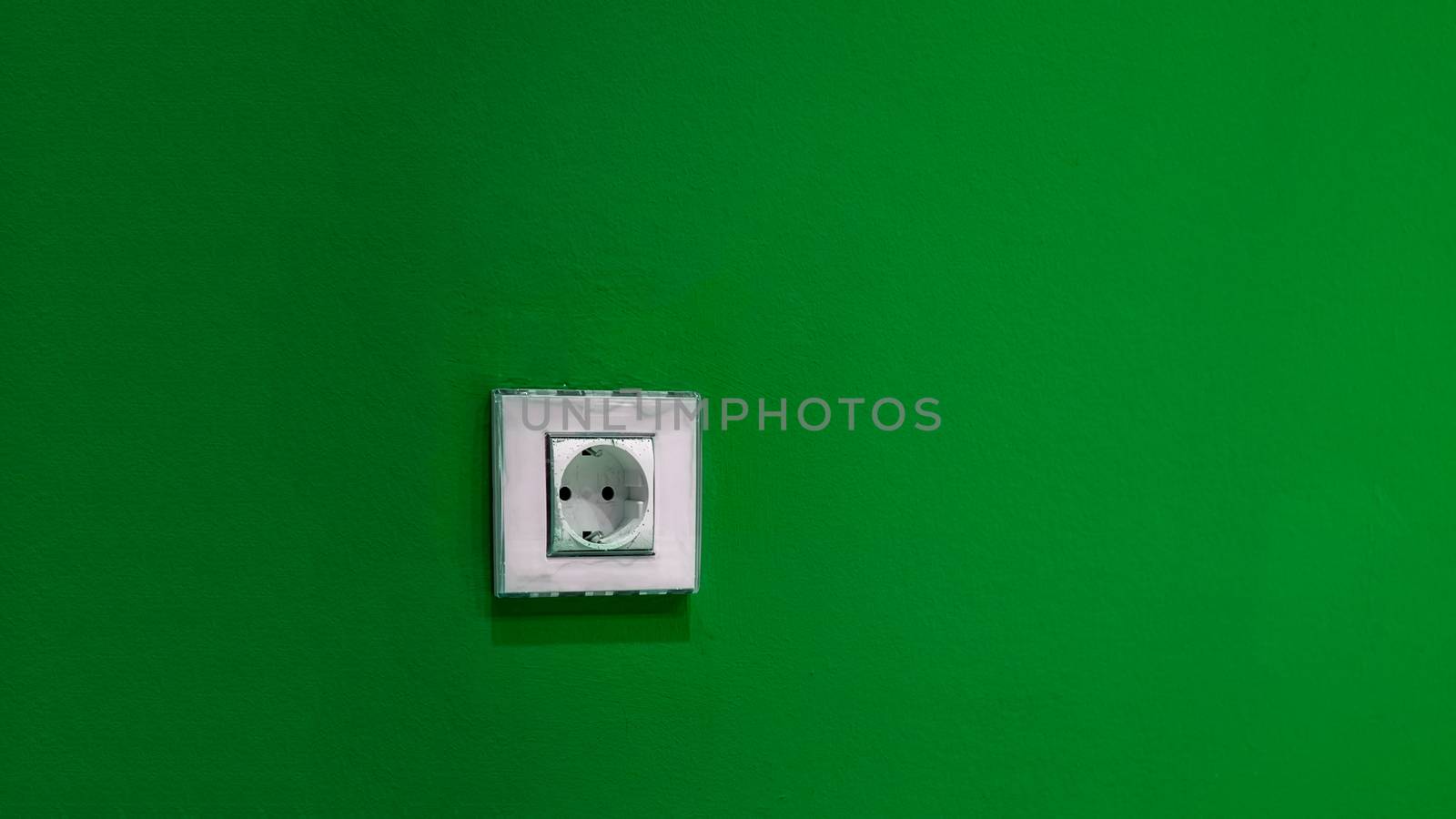 a white socket on the green wall