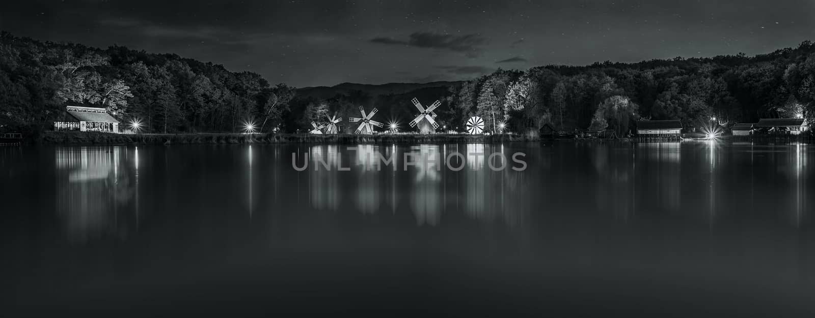Landscape panorama with windmills at the blue hour in White Night of the Museums. Dumbrava lake, Astra Museum of Traditional Folk Civilization, Sibiu city, Romania