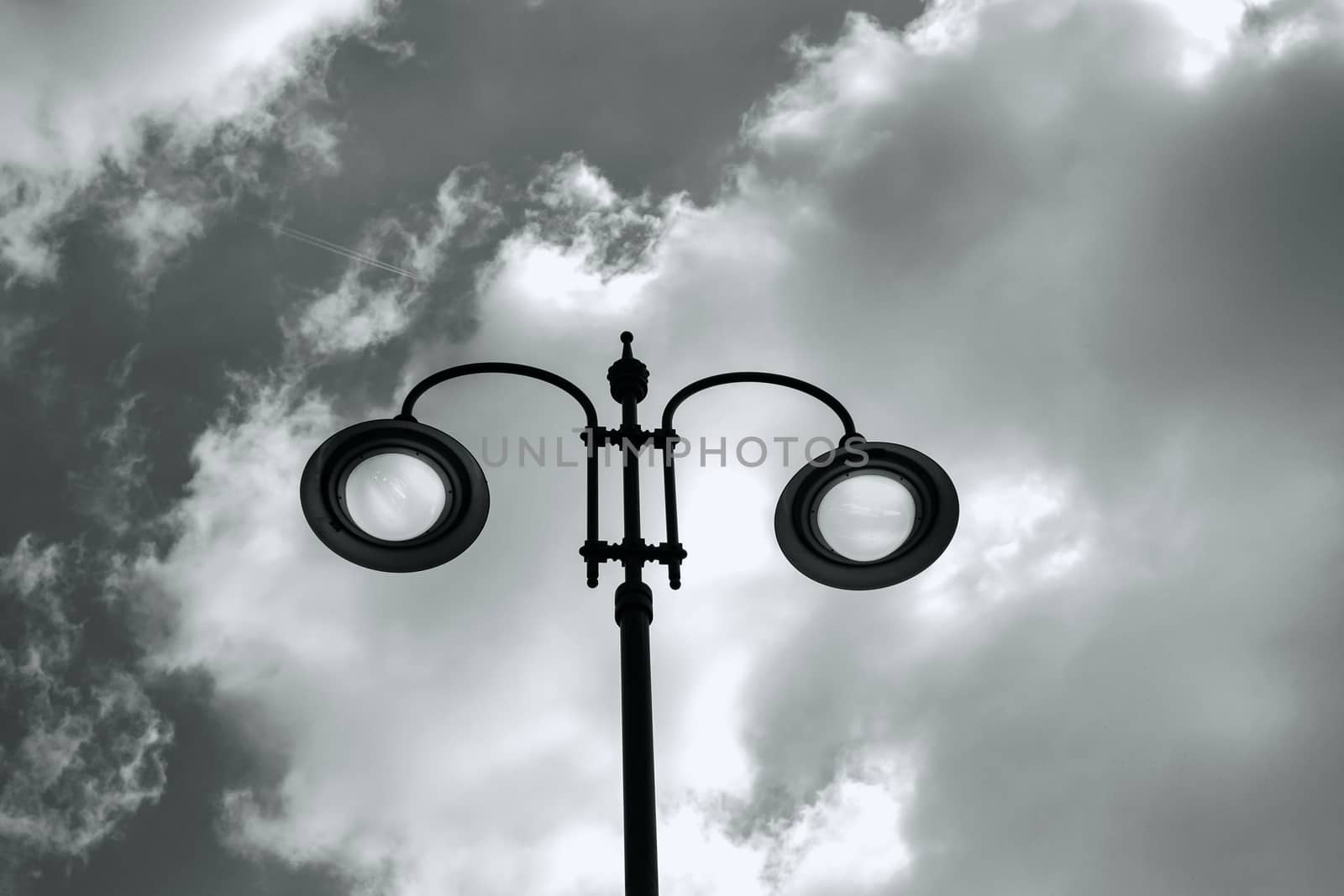 city lit light pole on day with cloudy sky