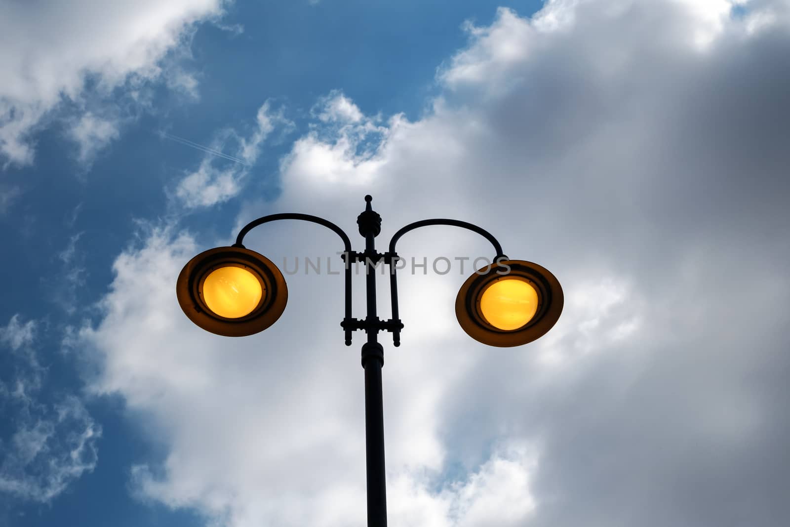 city lit light pole on day with cloudy sky