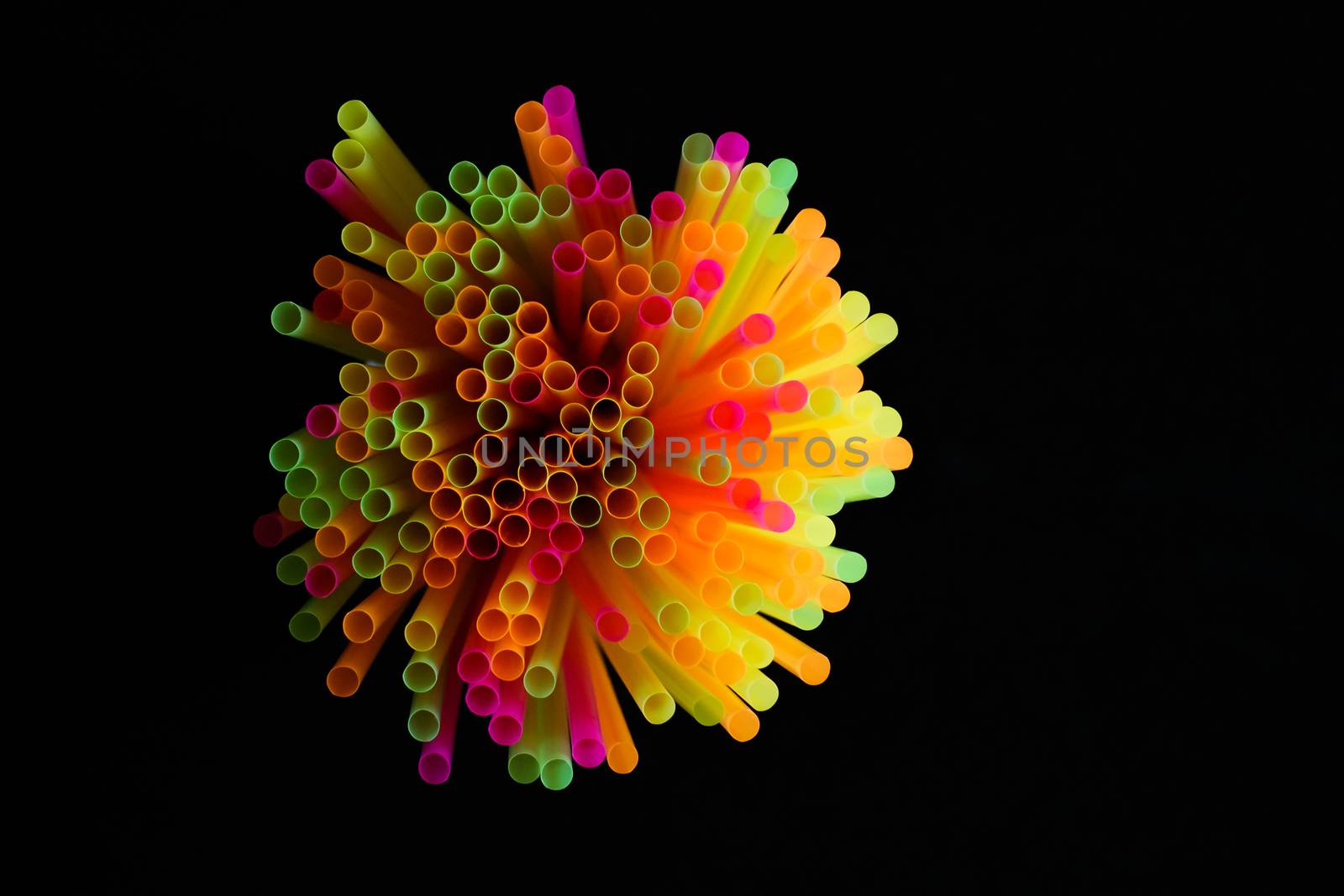 colored plastic drinking straws on black background