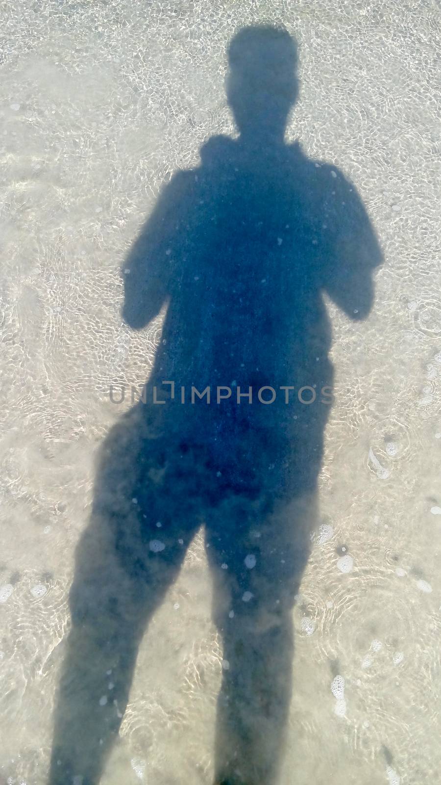 man and shadow stand on sea water surface