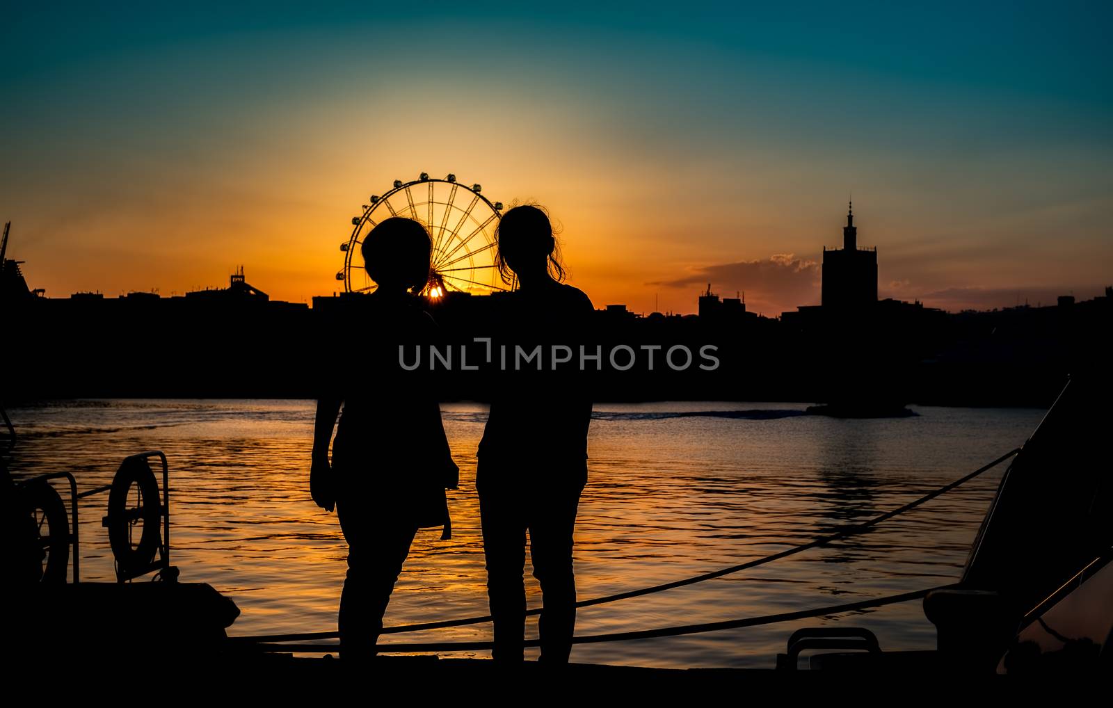 silhouettes of two young girls at sunset by Roberto