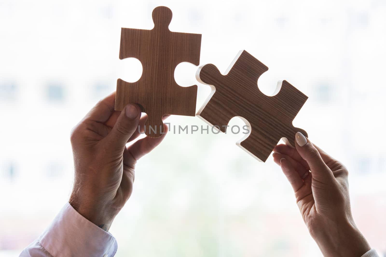 Male and female hands with puzzle pieces on white, business cooperation problem solution relationship concept