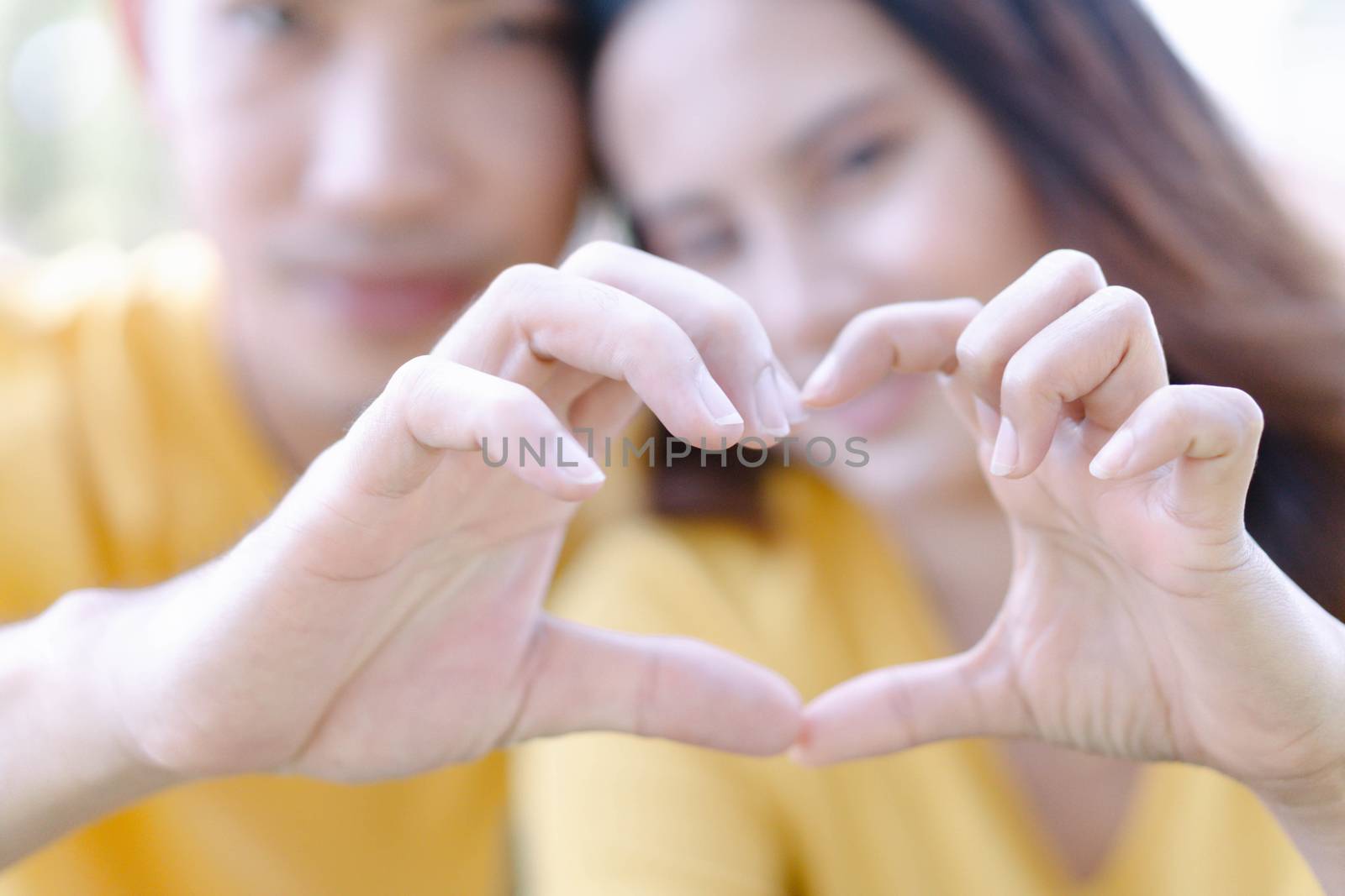 Closeup of couple making heart shape with hands in the park