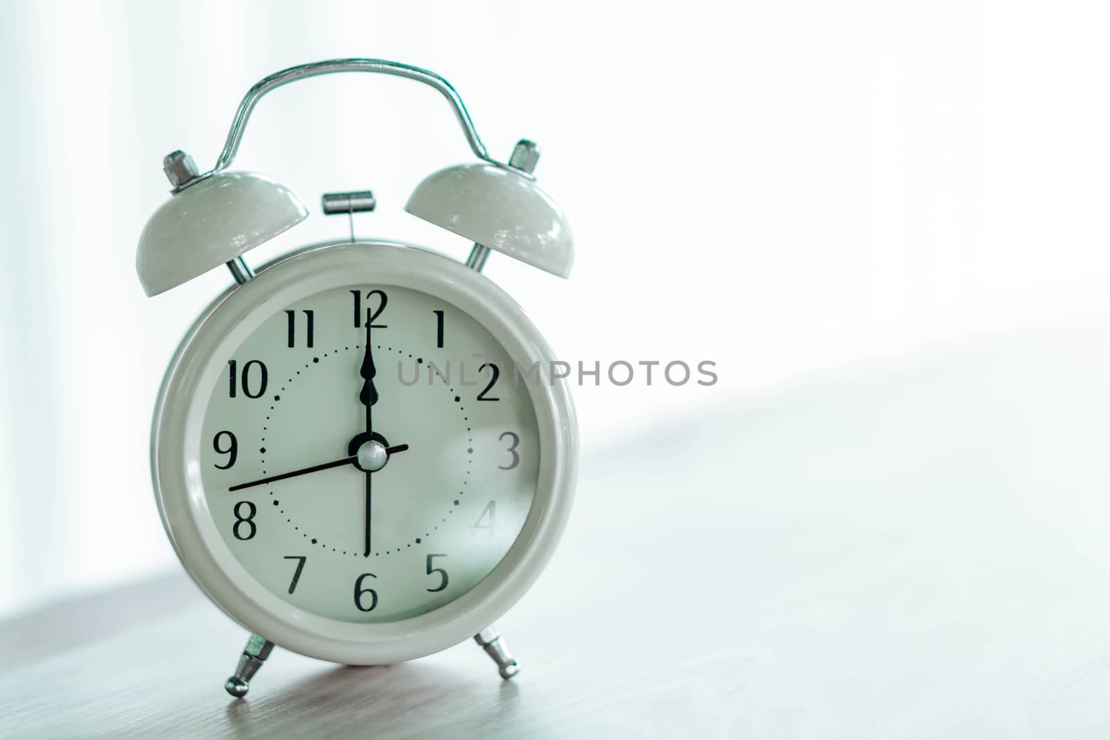 Alarm clock on white table with soft light in the morning, selective