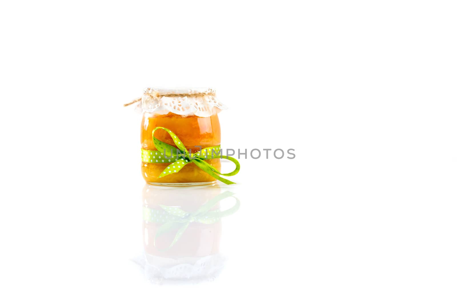 Glass jar with apricot jam isolated on white background.