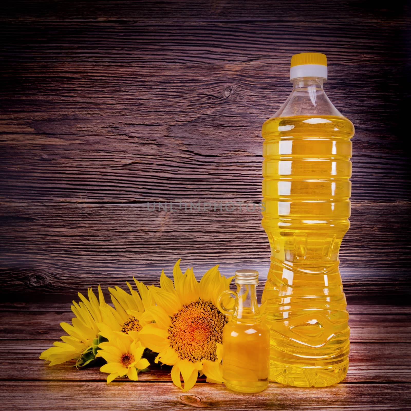 Sunflower oil with flowers on rustic wooden background. Studio shot.