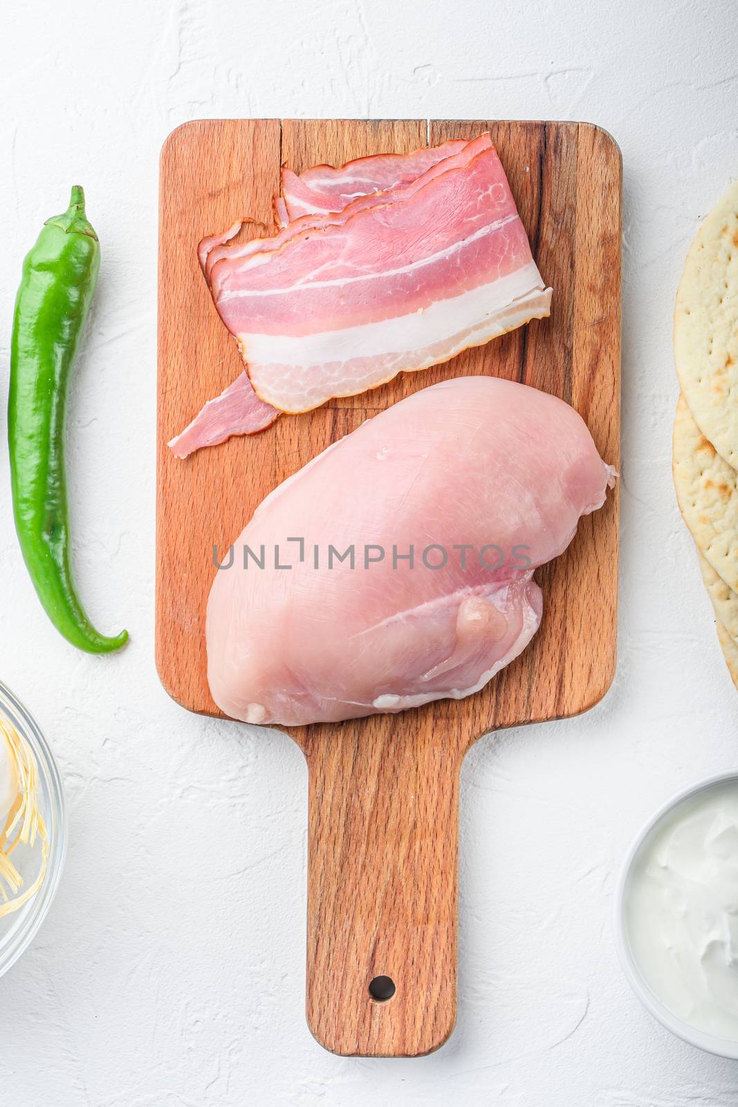 Chicken brest for mexican tacos ingredients on chopping board over white textured backgroundside view