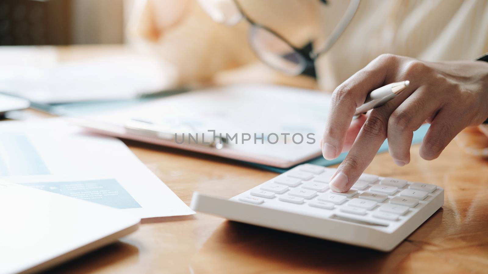 Close up Businesswoman using calculator and laptop for do math finance on wooden desk in office and business working background, tax, accounting, statistics and analytic research concept
