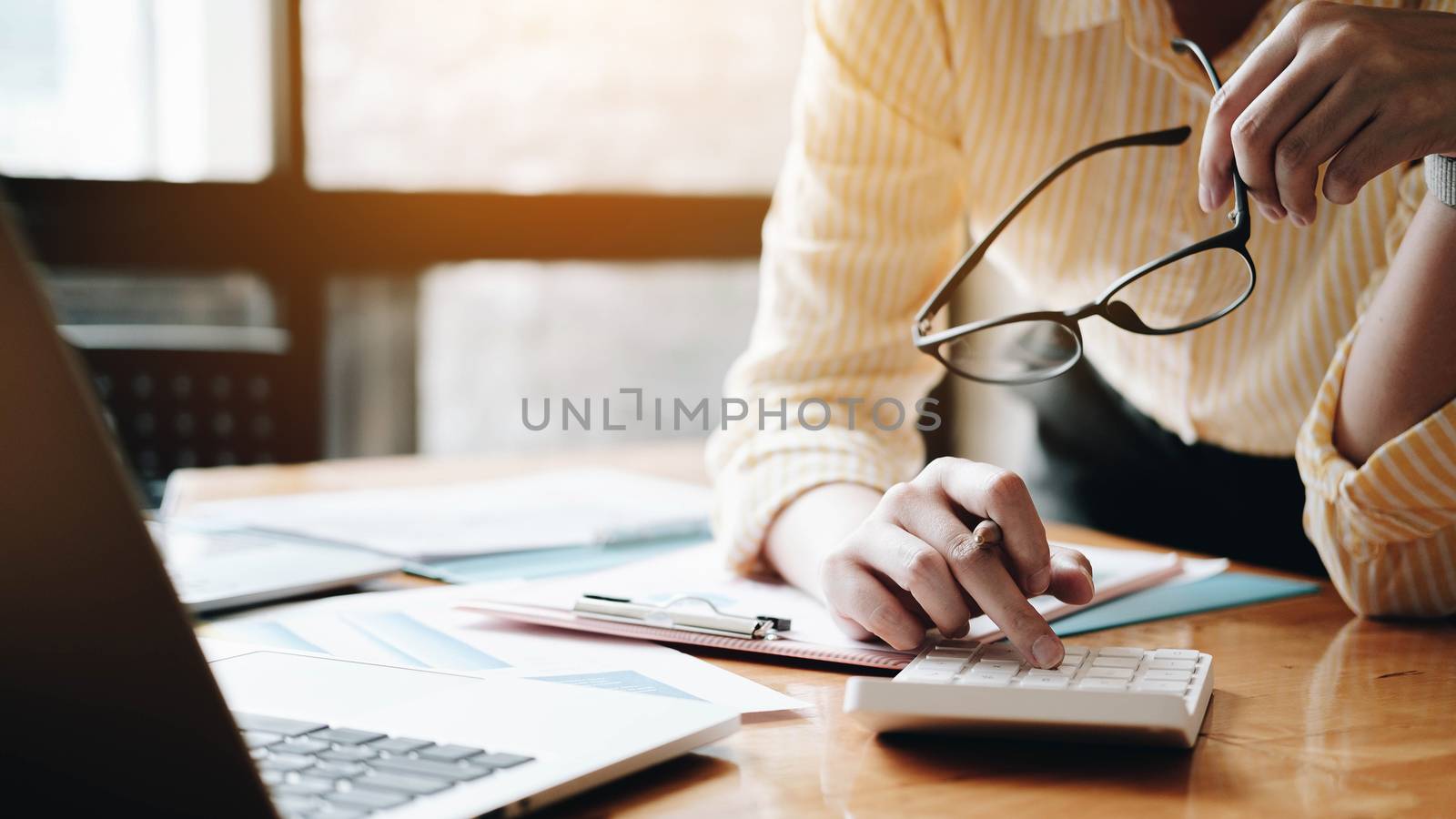 Close up Business woman using calculator and laptop for do math  by wichayada