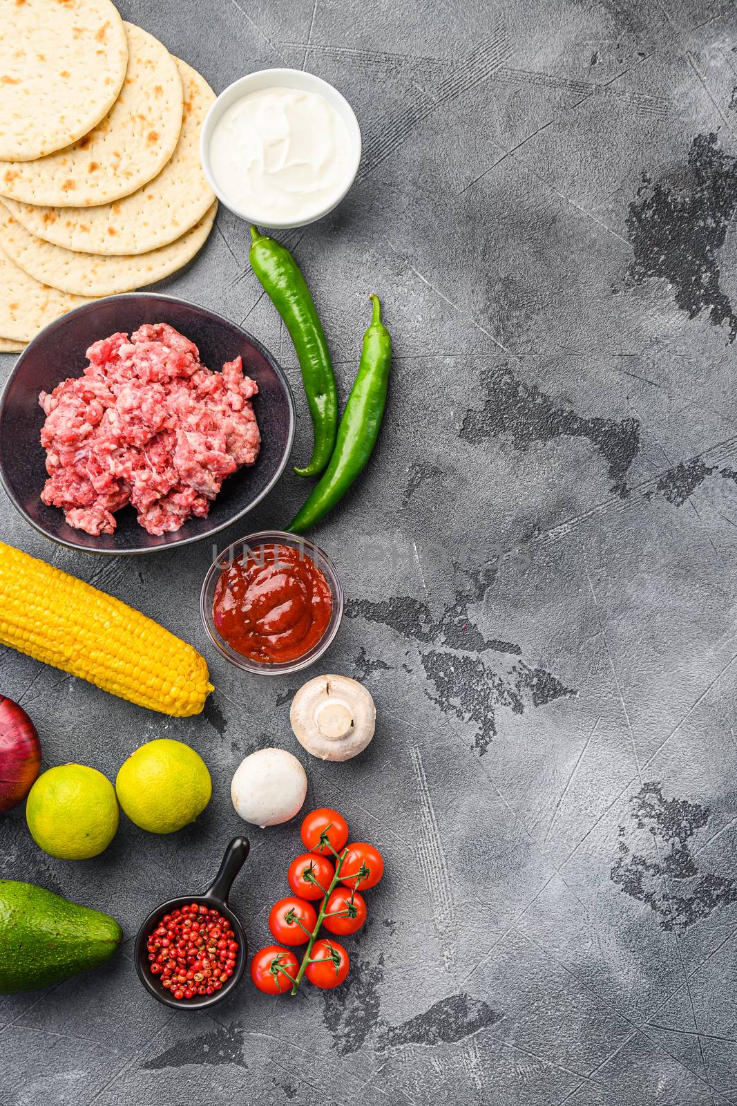 Ingredients for beef meat mexican tacos , corn tortillas, chili pepper, avocado, meat on textured grey background, top view vertical with space for text