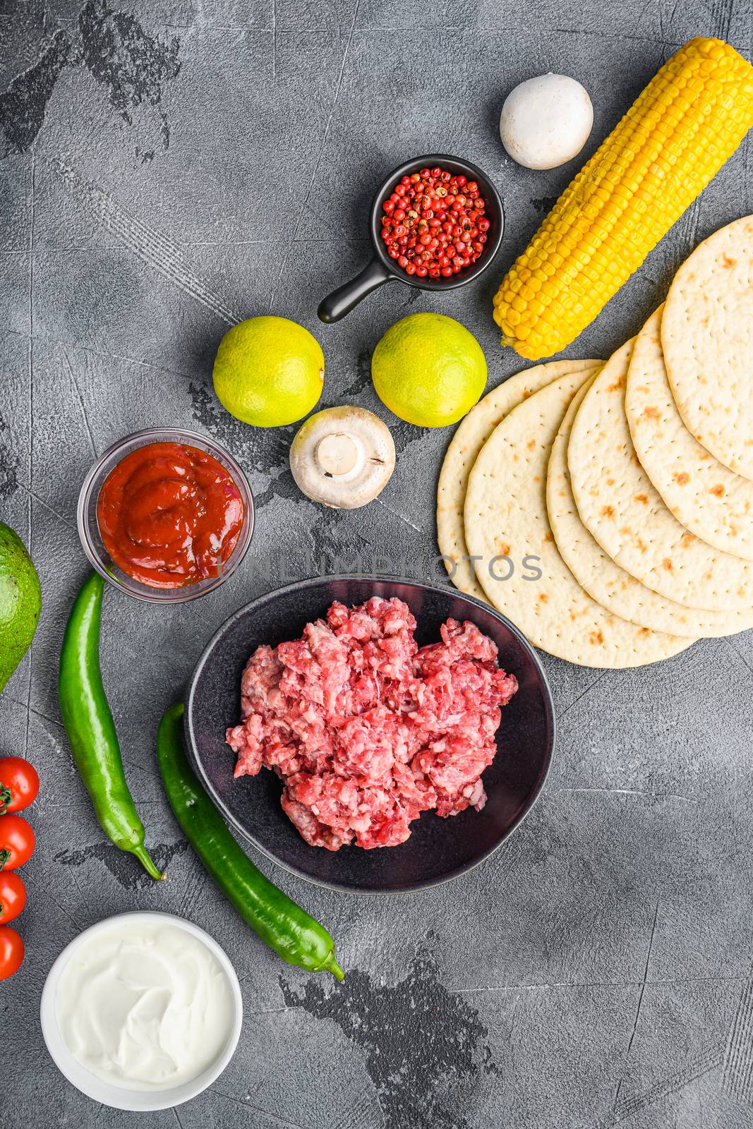 Traditional homemade taco ingredients with meat over grey background, top view