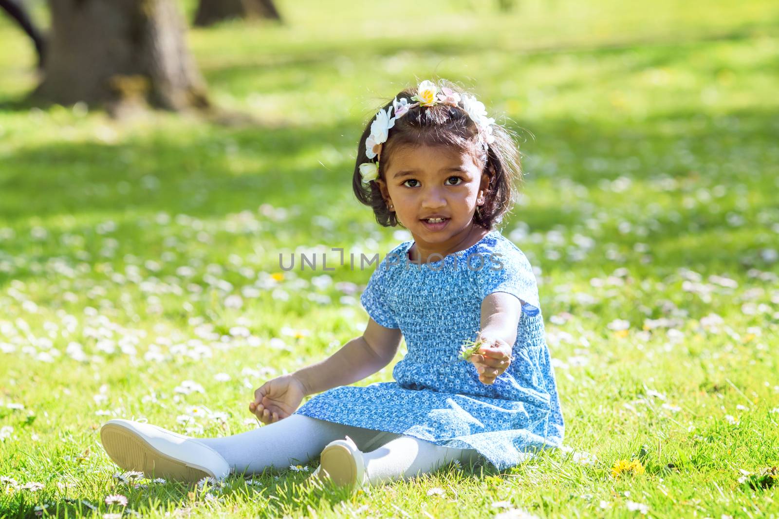 A asian little girl siting on green grass in spring park