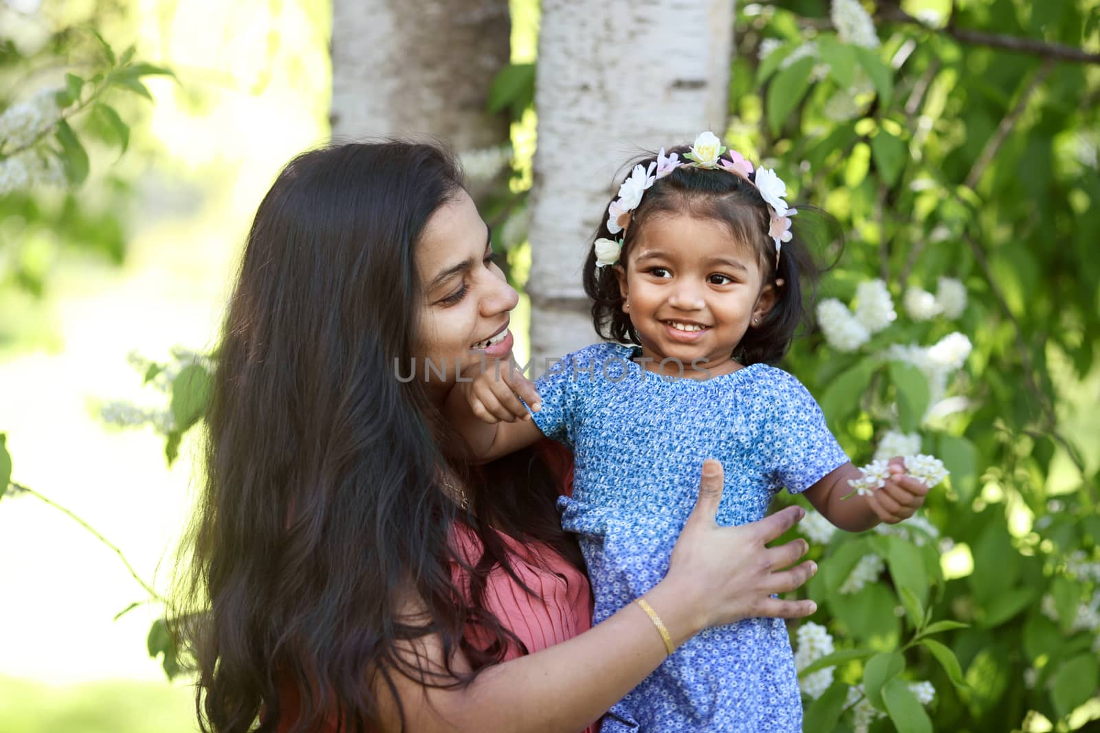 A happy swarthy woman with her daughter in spring park by anry