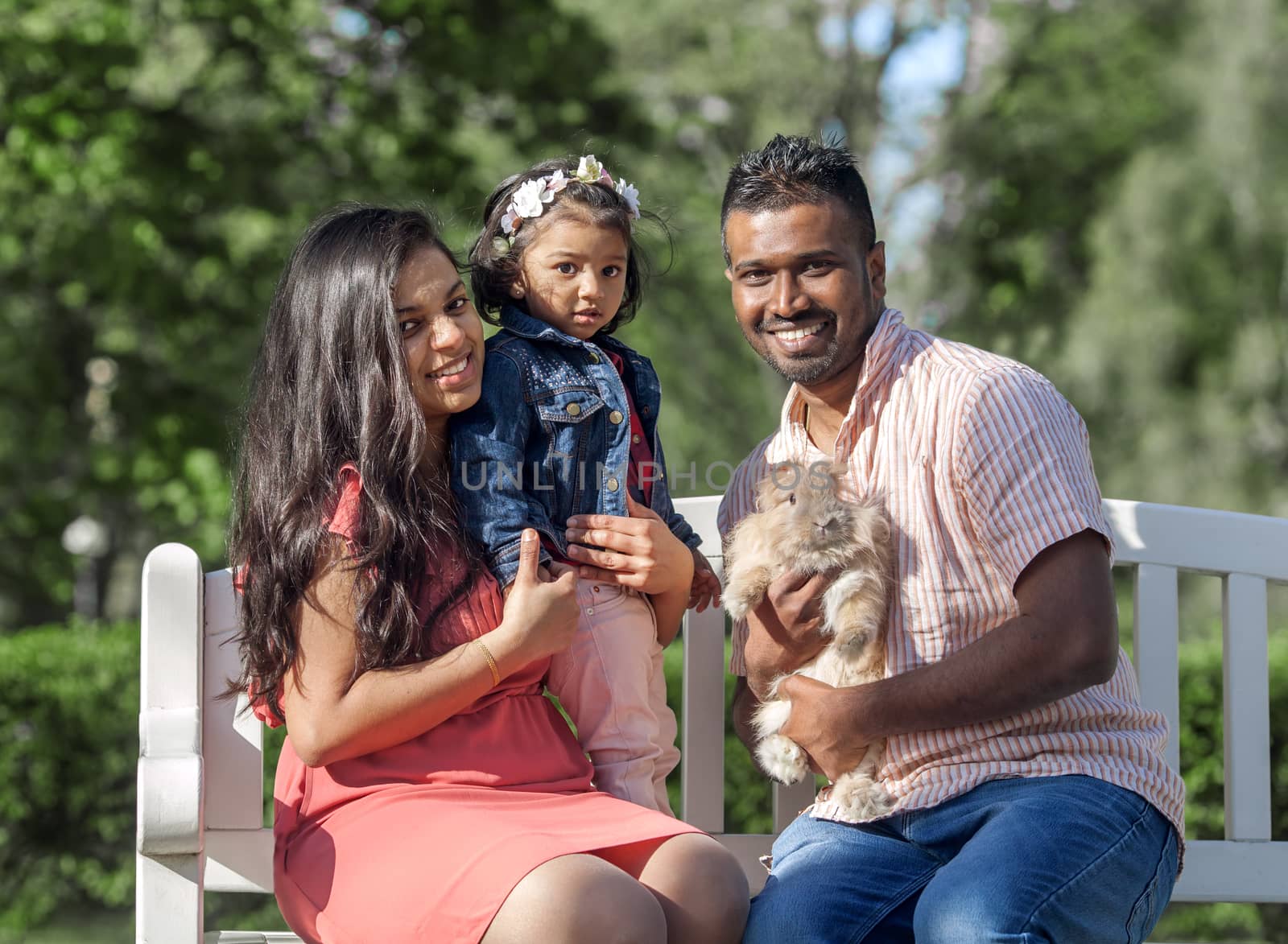 happy family father, mother and small girl with rabbit in a city park by anry