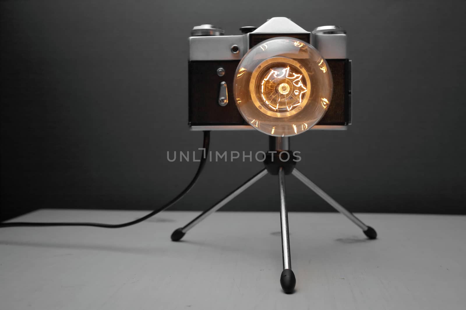 Retro lamp from an old camera with an Edison lamp on a gray background. Concept is a good idea. High quality photo