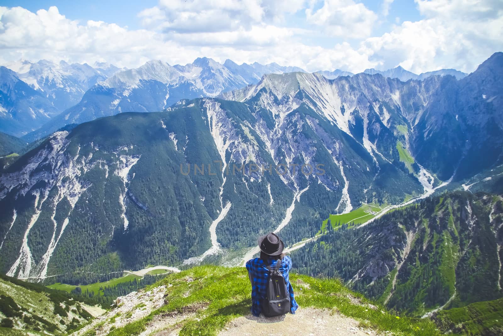 Woman traveller sitting admiring the scenery of the Alps mountains. by anotestocker