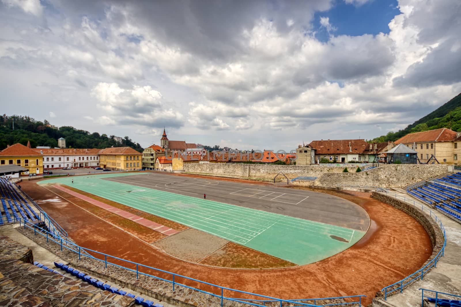 BRASOV, ROMANIA - Circa 2020: empty sport stadium and running track with moody cloudy sky. Concept of outdoor activities. No outdoor activity due to lock down. by dugulan