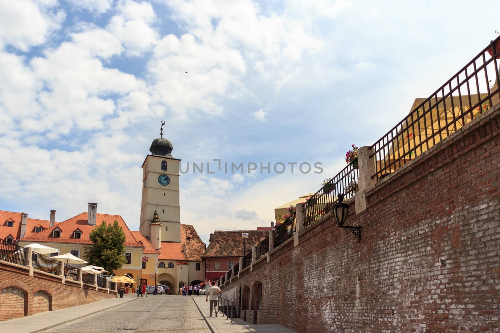 SIBIU, ROMANIA - Circa 2020: Old medieval town brick wall with cloudy blue sky. Beautiful tourist spot in eastern central Europe. Famous Tower of Council in Sibiu Romania by dugulan