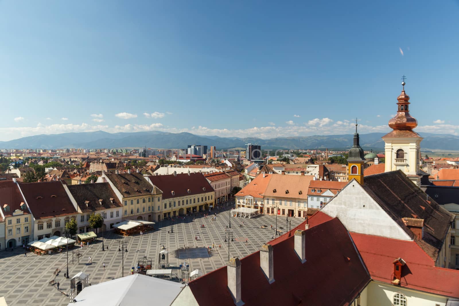 SIBIU, ROMANIA - Circa 2020: High view of old medieval town with cloudy blue sky. Beautiful tourist spot in eastern central Europe. Aerial view of famous Big Square in Sibiu Romania by dugulan