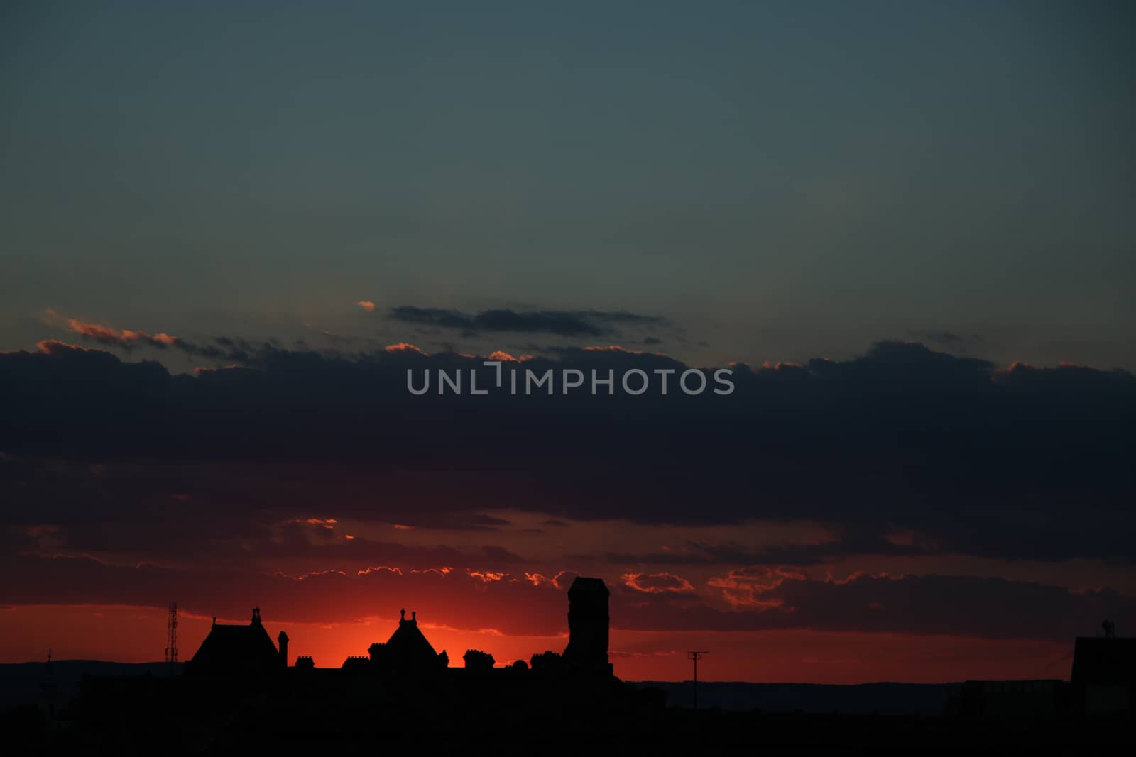 Concept of calm and serenity. Colorful and cloudy sunset in the background. Sibiu, Romania, old medieval town in eastern central Europe. Fiery red sunset with old building silhouette.