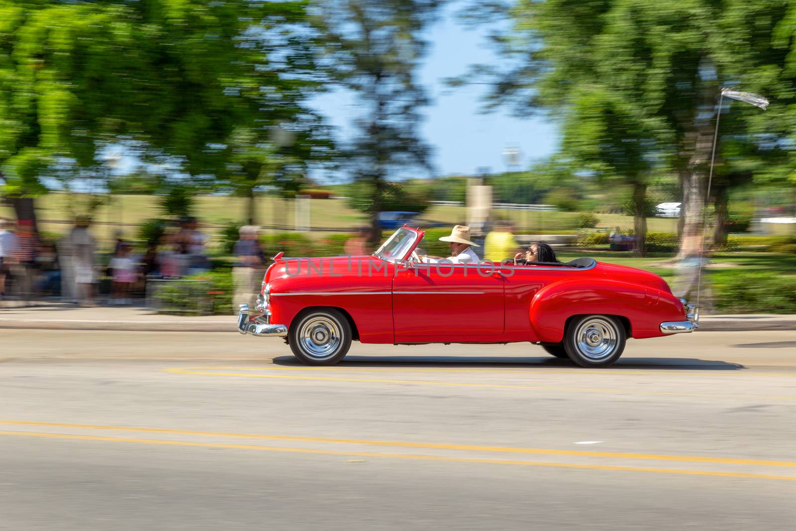 HAVANA, CUBA - CIRCA 2017: Panning on an American red classic car in the streets of Havana, transporting tourists. Concept of tourism having fun.