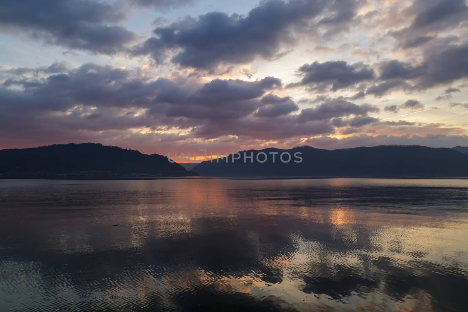 Amazing natural landscapes, Beautiful colorful sunrise, sunset with hills on the background and reflection on the Danube River in Orsova, Romania.