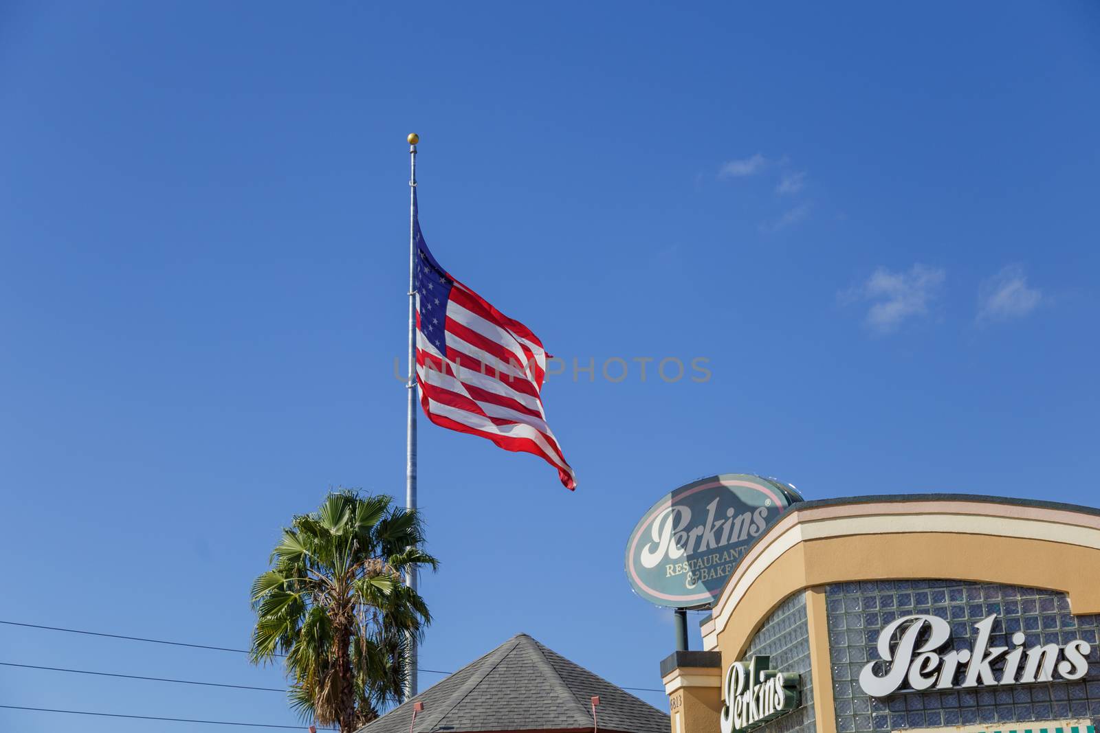 Orlando, Florida, USA - CIRCA, 2019: : Perkins Family Restaurant and Bakery Location with American flag flying over a bright blue sky by dugulan