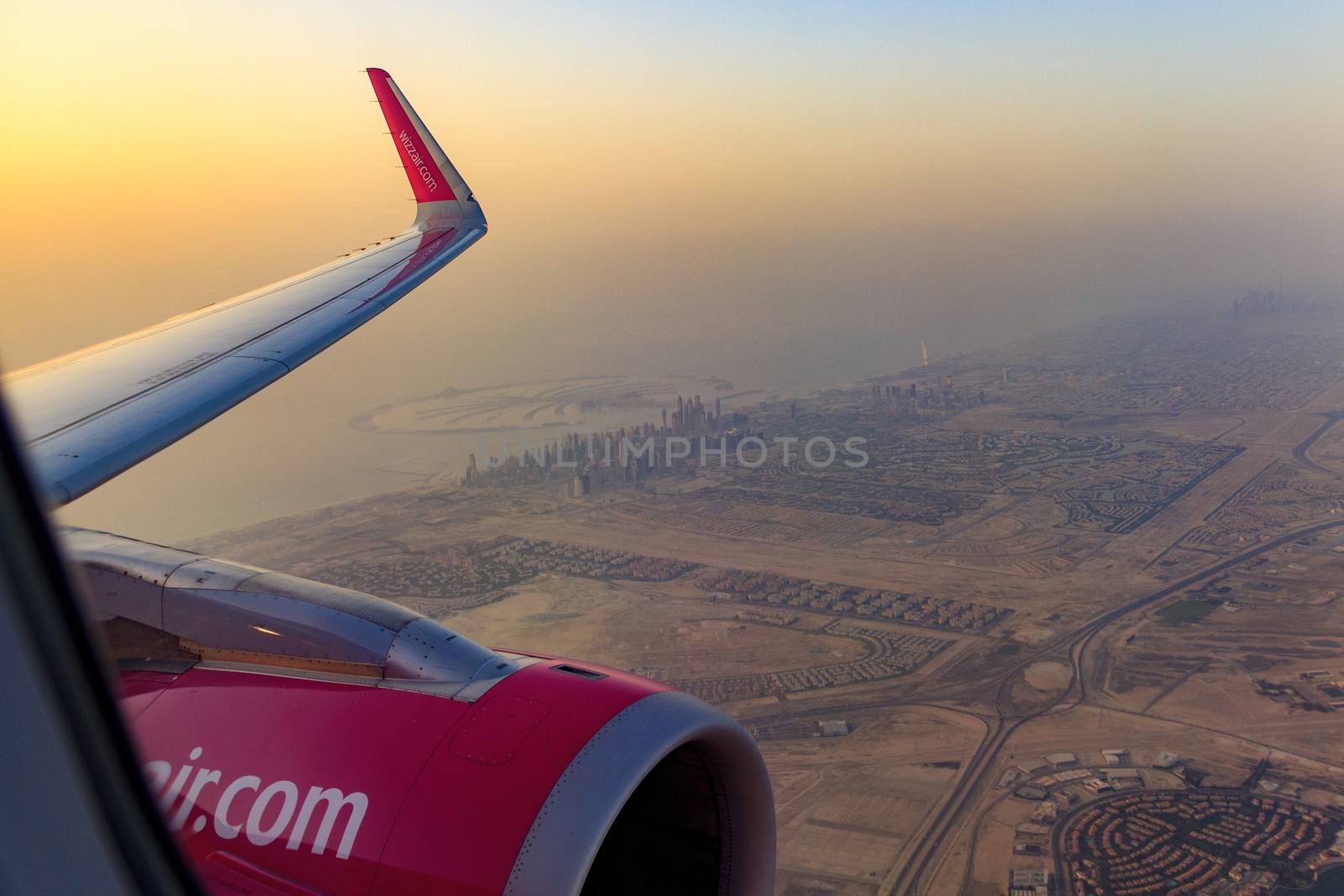 DUBAI, UAE - CIRCA 2020: View of Dubai skyline from an airplane during a colorful sunset. View of Persian Golf and Dubai skyscrapers. by dugulan