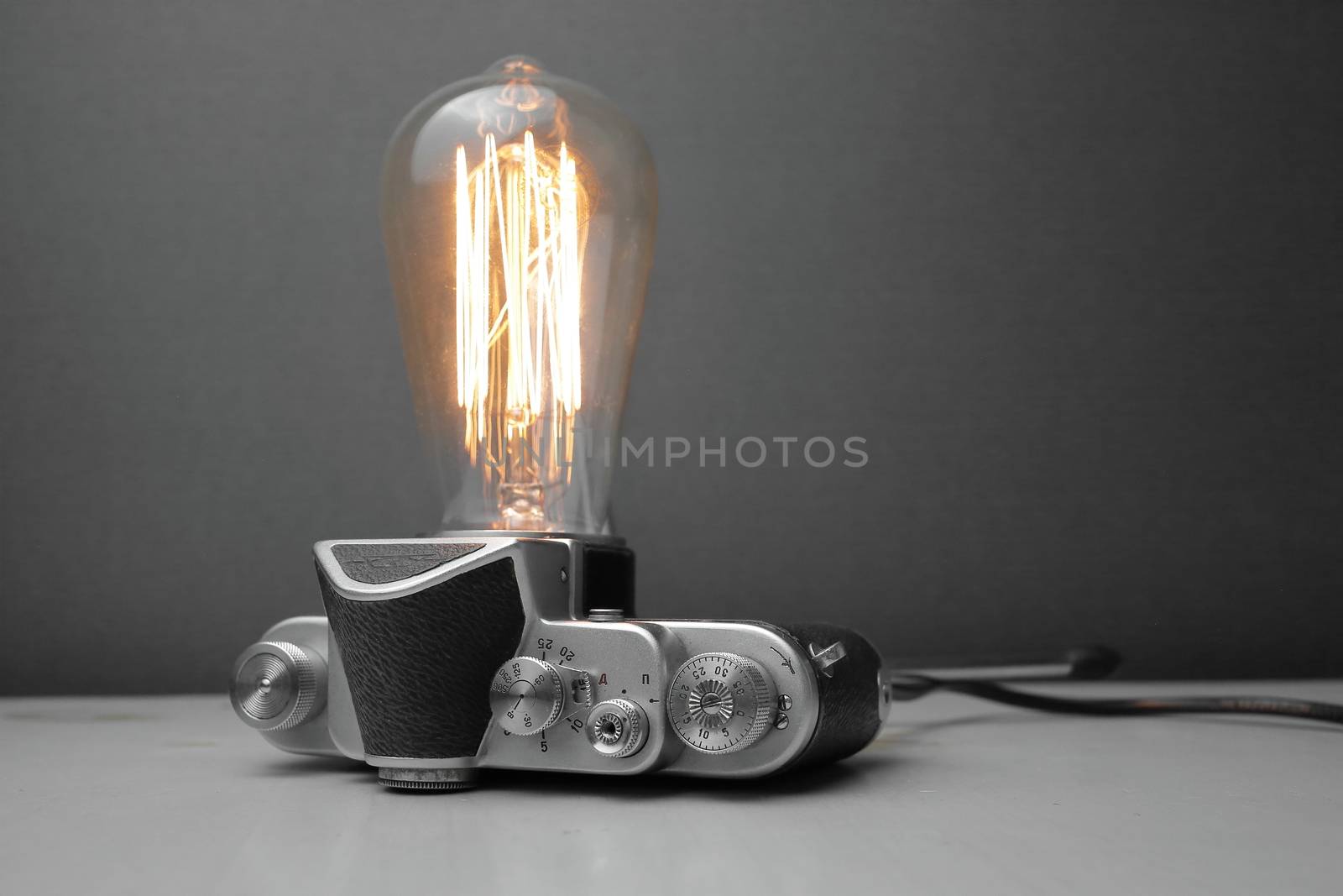 Retro lamp from an old camera with an Edison lamp on a gray background. Concept is a good idea. High quality photo