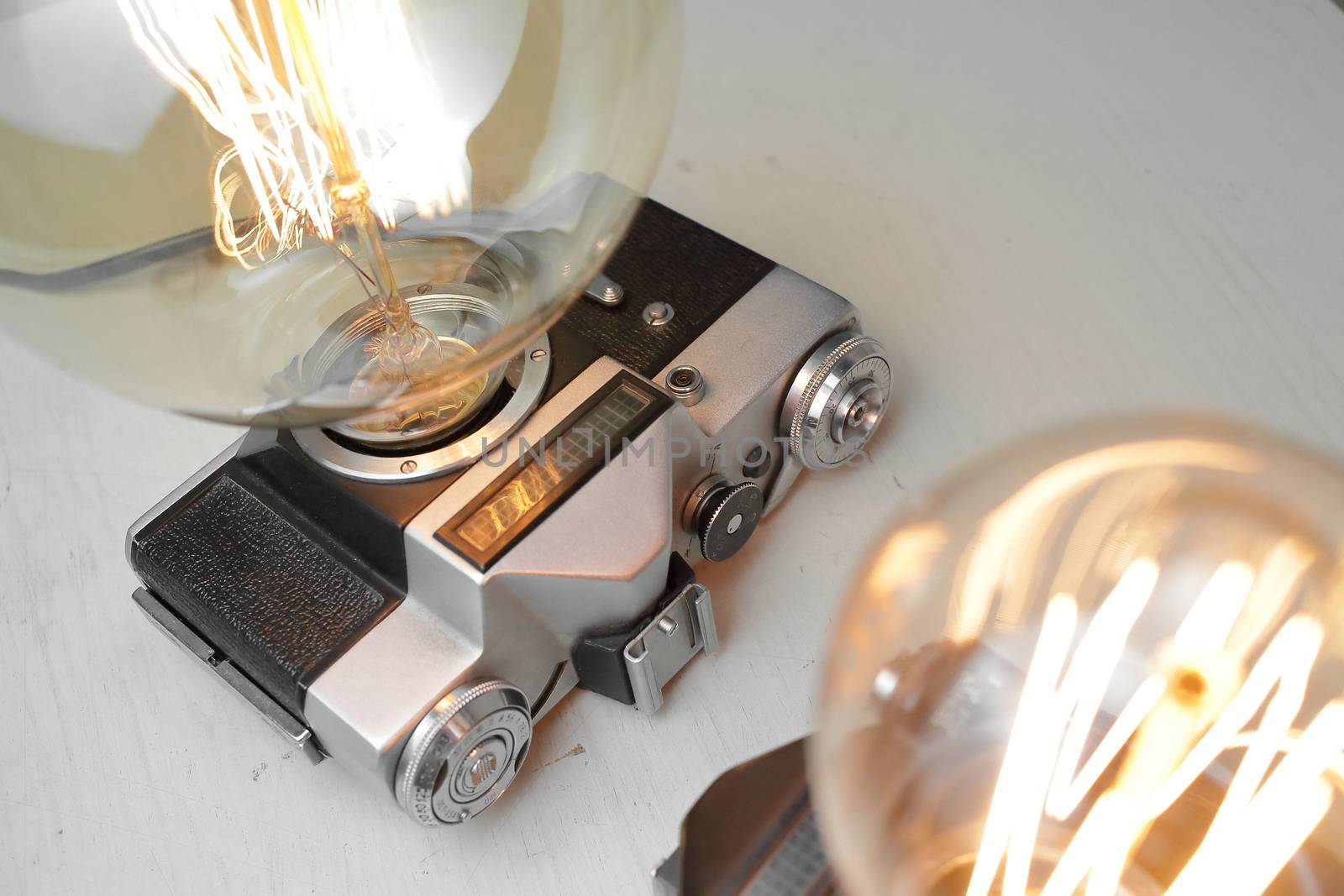Retro lamp from an old camera with an Edison lamp on a gray background. Concept is a good idea. by selinsmo