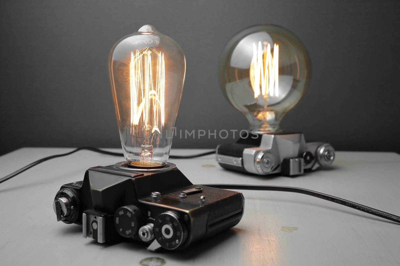 Retro lamp from an old camera with an Edison lamp on a gray background. Concept is a good idea. by selinsmo