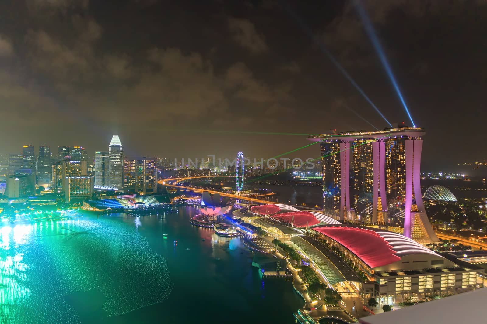 Singapore - CIRCA 2020: Skyline in Marina Bay, view of Art Museum, famous hotel and Singapore Flyer during the night with a stormy sky on the background and lasers and light show before New Year Eve