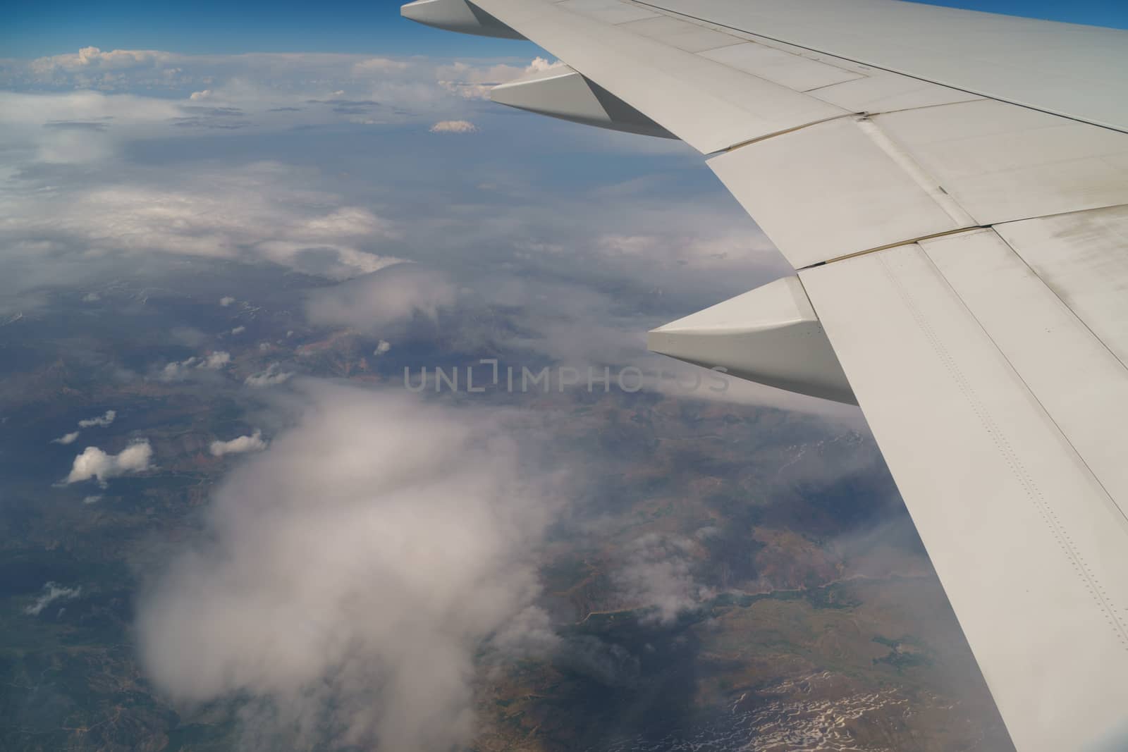 Flying and traveling, view from airplane window on the wing on a cloudy day. Wing of an airplane flying above the morning clouds. by dugulan