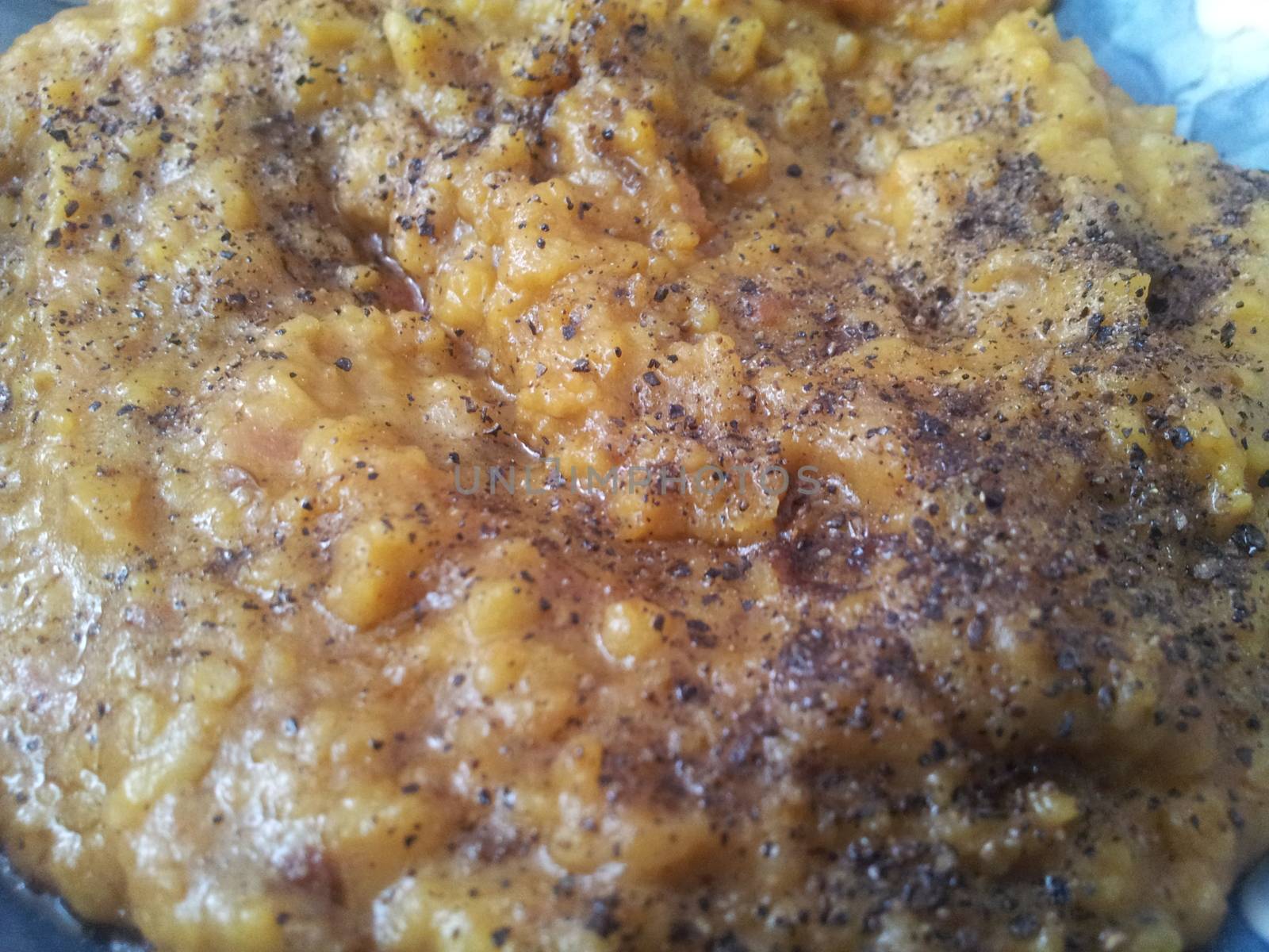 A close up view spicy daal dish served with ghee on it. by Photochowk