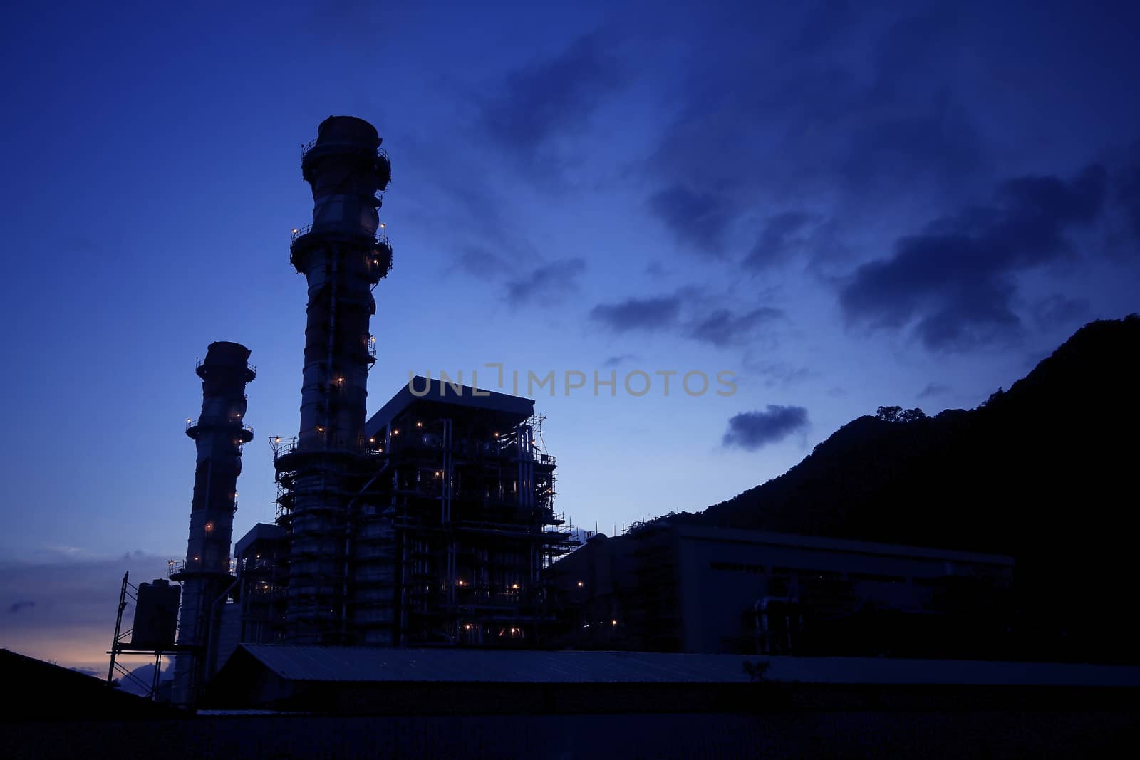 The silhouette of a black industrial factory chimney