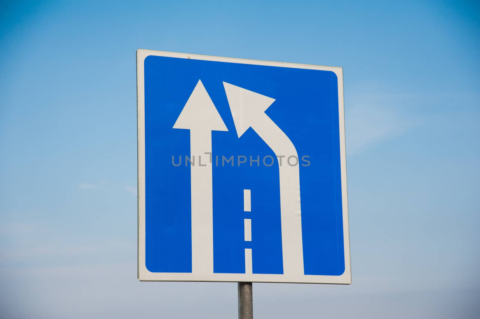Road sign: end of lane. Road sign against a blue sky.